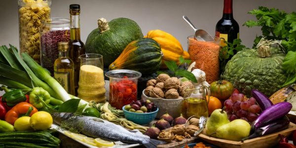 Mesa farta com alimentos da dieta mediterrânica incluindo peixe fresco, azeite de oliva, nozes, legumes, lentilhas, uvas e abóboras.