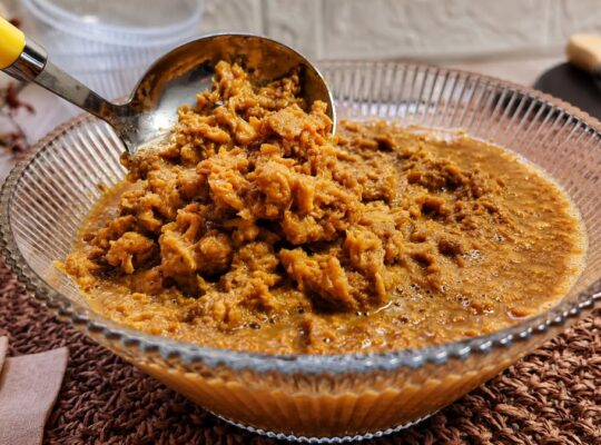 Doce de ambrosia cremoso e grumoso em calda de caramelo em uma tigela de vidro com concha de servir.
