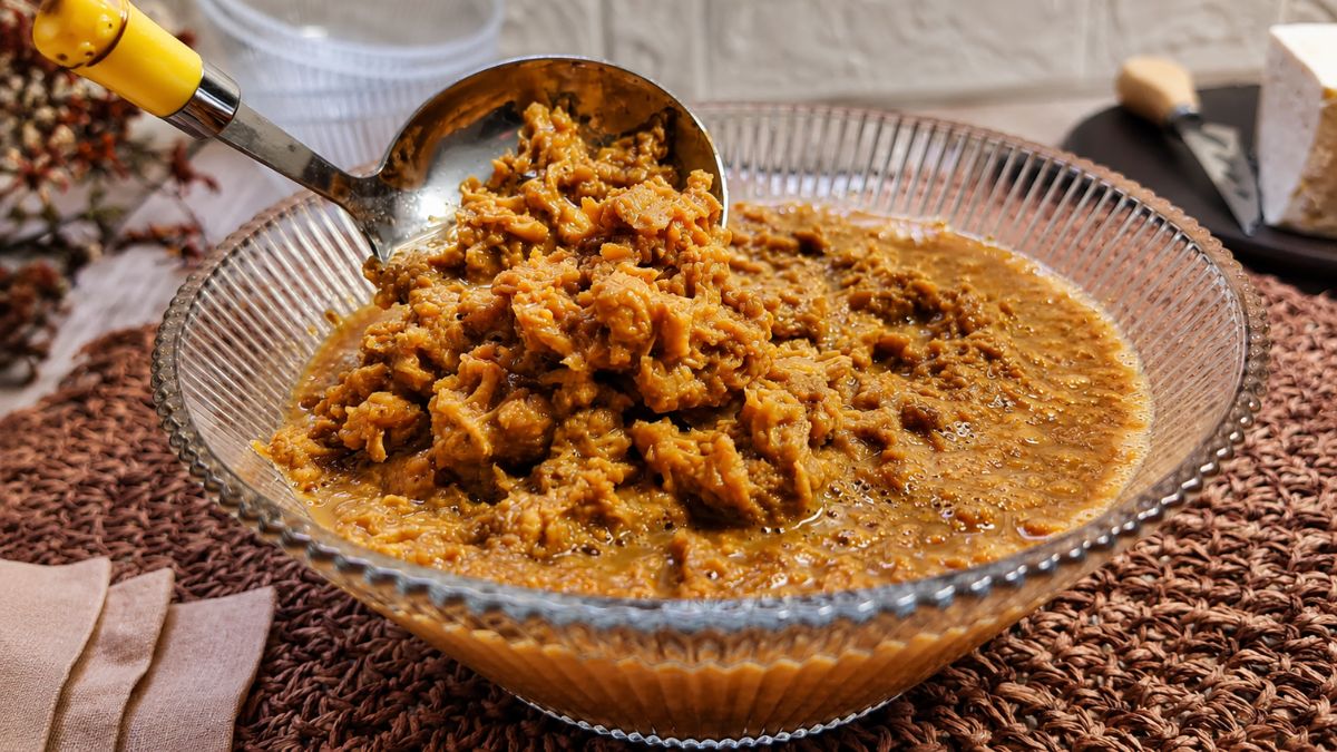 Doce de ambrosia cremoso e grumoso em calda de caramelo em uma tigela de vidro com concha de servir.