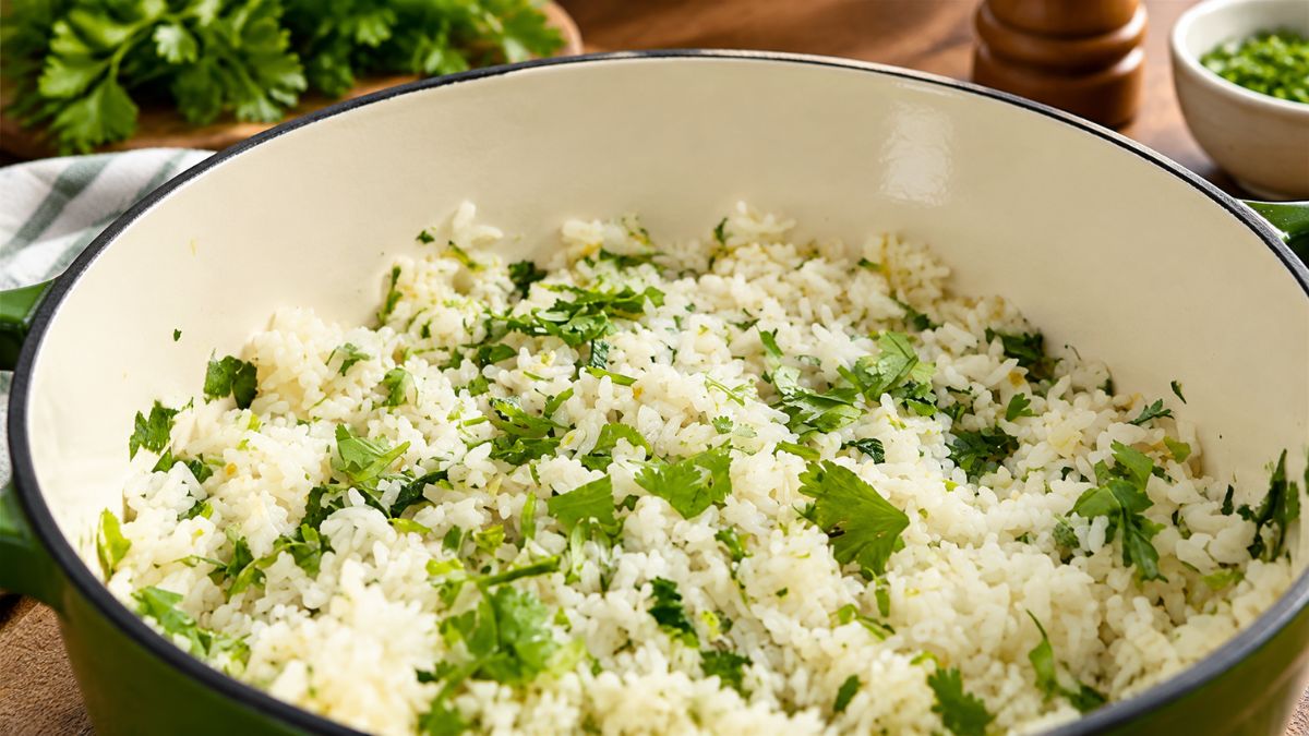Tacho com arroz de coentros solto salpicado com coentros frescos picados, um acompanhamento tradicional da culinária portuguesa preparado com azeite e alho.