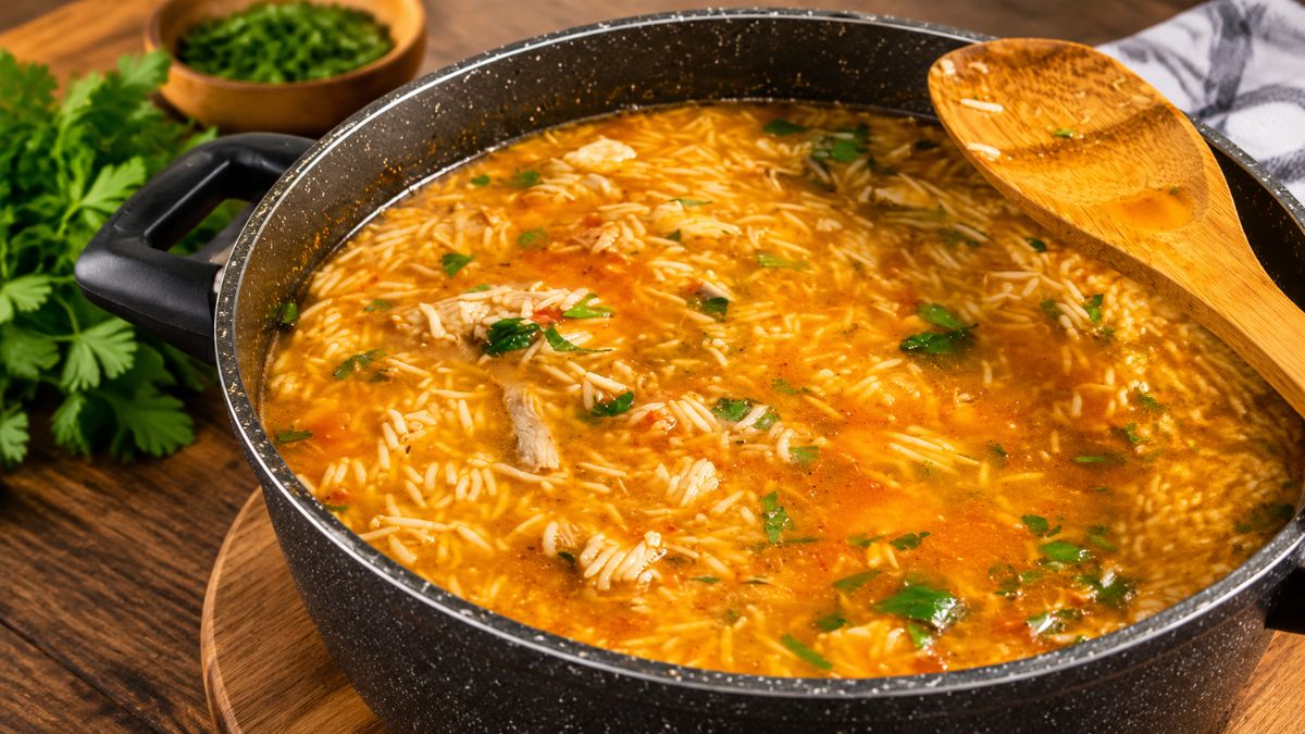 Tacho com arroz de garoupa malandrinho temperado com salsa fresca e servido com colher de pau em mesa de madeira.