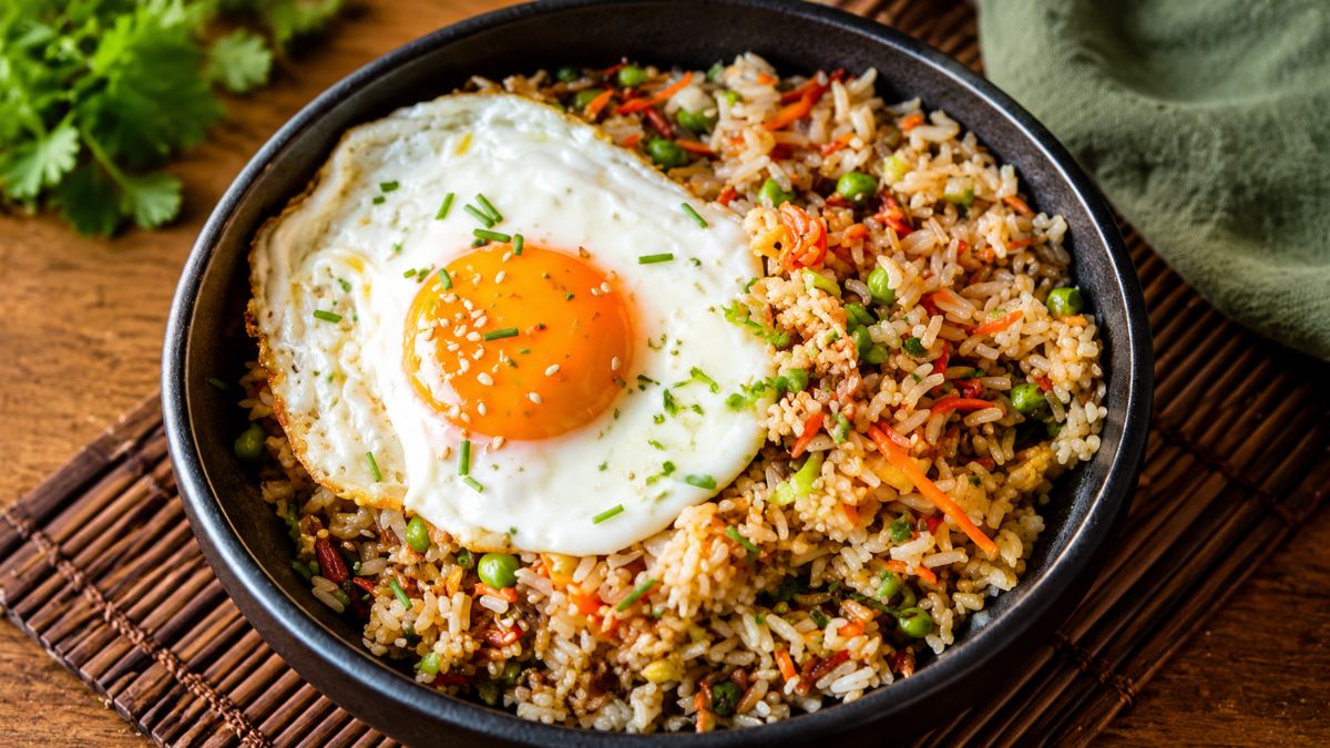Prato fundo de arroz de polvo salteado com vegetais e um ovo estrelado perfeito no topo.