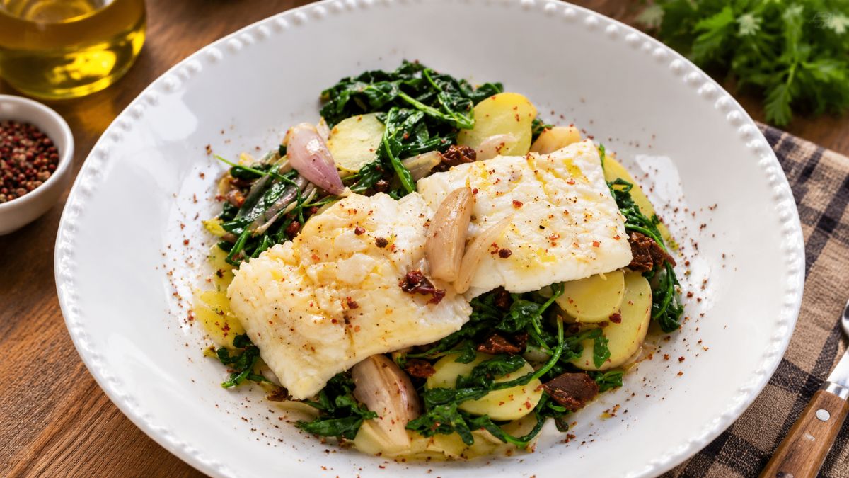 Prato gourmet de lombos de bacalhau confitado em azeite com batatas, rúcula salteada e tomate seco picado.
