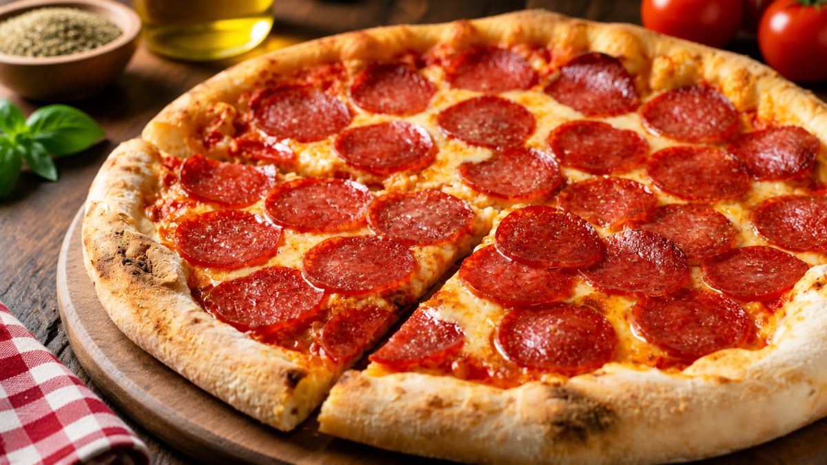 Uma pizza de pepperoni artesanal e recém-assada, servida sobre uma tábua de madeira rústica, com uma fatia levemente separada, revelando a base crocante.