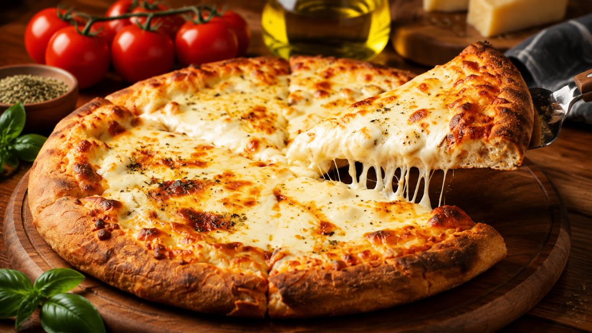 Uma fatia de pizza de queijo derretido sendo levantada com queijo puxando e um fundo rústico de madeira com tomate cereja manjericão azeite e orégano.