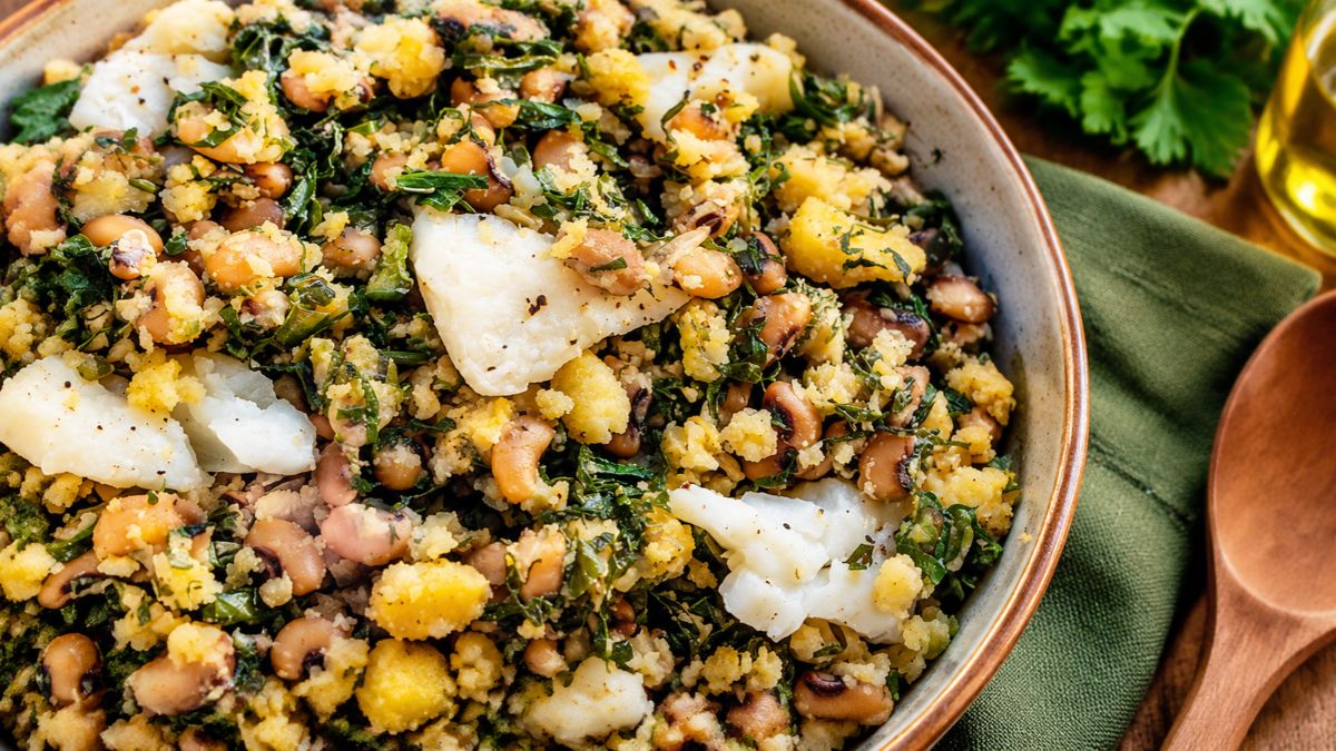 Migas de bacalhau tradicionais servidas numa tigela de cerâmica com lascas de bacalhau, miolo de broa de milho, feijão frade e couve cortada em caldo verde.